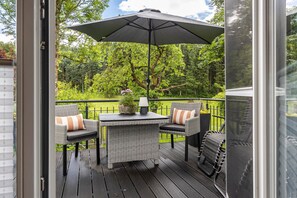 An outdoor deck with wicker furniture, a table, and an umbrella. - Apartment Auf'm Hühnerstall, 60 sqm, 1 Bedroom, Max. 2 Guests (Lennestadt)