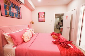 Een hotelkamer in roze tinten, met een groot bed, een poster met Barbiepoppen en een bordje 'Alleen voor meiden' op de deur.
