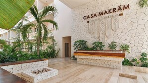Eine geräumige Lobby mit Steinwand, einer Rezeption und tropischen Pflanzen.