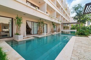 A modern hotel with a swimming pool, outdoor seating, and lush greenery. - Tulum Swim-Up Studio w/ Private Plunge Pool (Tulum)