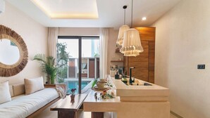 Ein modernes Wohnzimmer mit Sofa, Couchtisch und Küchenzeile mit einer Theke und Pendelleuchten.