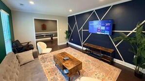 Een moderne woonkamer met een bank, salontafel en een tv die boven een kamerbreed tapijt is bevestigd.