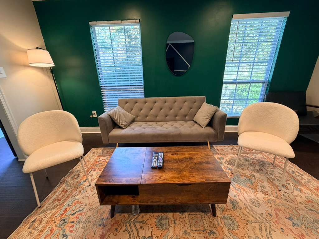 Un salon comprenant un canapé, deux fauteuils, une table basse et une lampe.