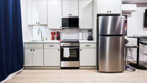 A modern kitchen with white cabinets, a stainless steel refrigerator, an oven, and a microwave. - Superhero Stay Marvel Fan Paradise. (Philadelphia)