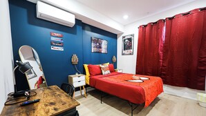 Une chambre à coucher avec un lit, un bureau, une chaise, un miroir et un rideau rouge.