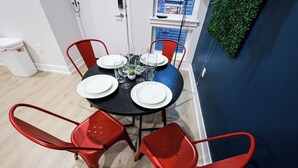 Un coin repas avec une table ronde dressée pour quatre personnes, entourée de chaises rouges.