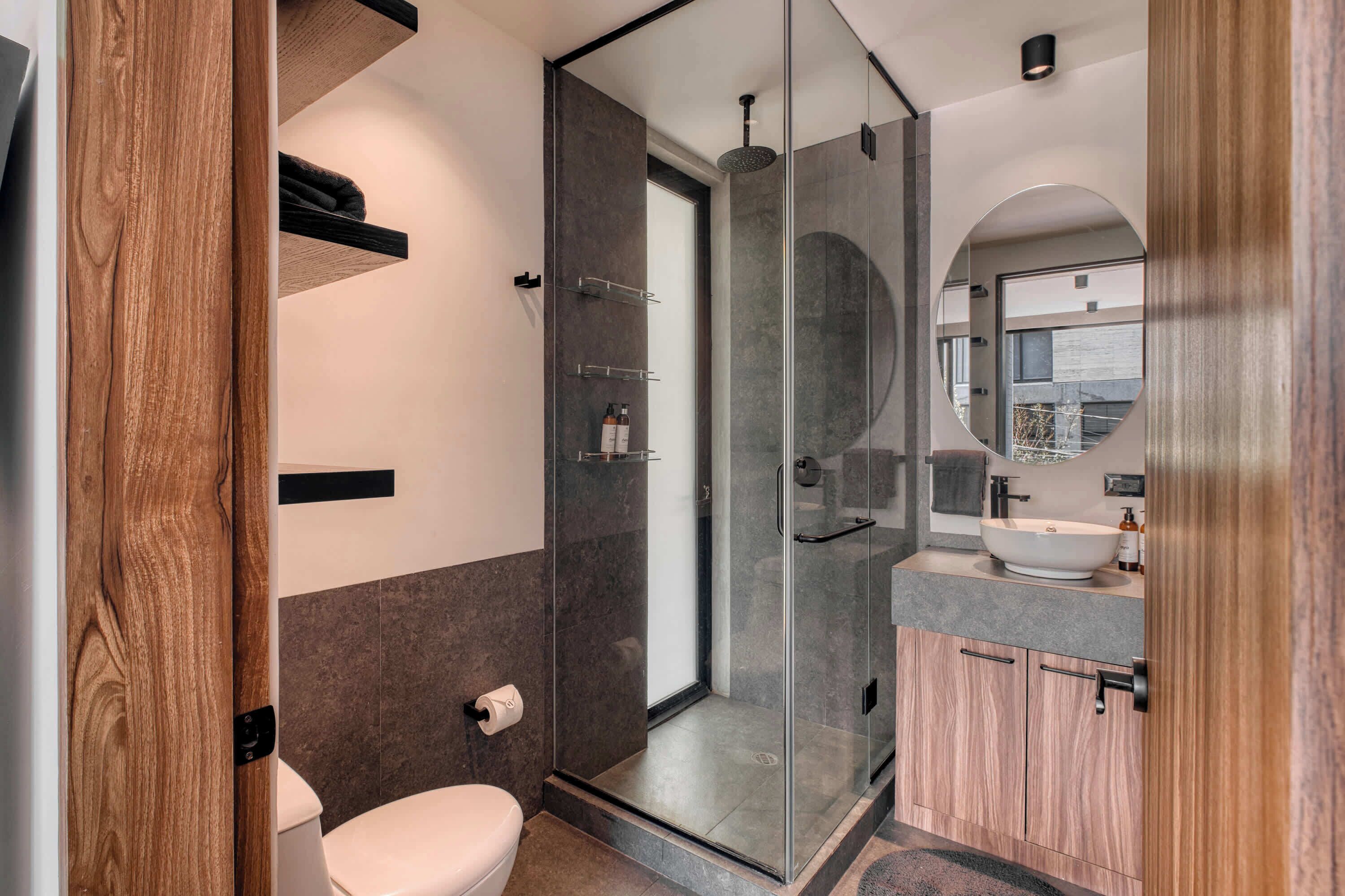 Un baño moderno con ducha envuelta en vidrio, inodoro y tocador con espejo.