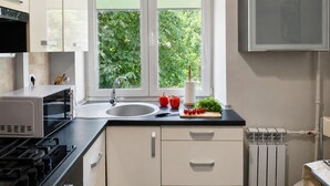 A modern kitchen with a window, a sink, a stove, and cabinets. - Apartment near Komarovsky Market (Minsk)