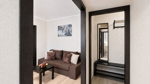 A modern living room with a brown sofa, a coffee table with fruit, a painting on the wall, and a mirror with a black frame. - Apartment near Komarovsky Market (Minsk)