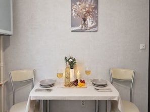 A dining table set with a bottle, glasses, a candle, and a fruit platter. - Apartment near Komarovsky Market (Minsk)