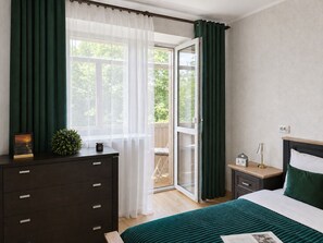 A bedroom with a bed, a dresser, a nightstand, a lamp, and a window with curtains. - Apartment near Komarovsky Market (Minsk)