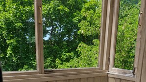 A wooden balcony with a cushioned chair, a table with croissants, a teapot, and glasses of tea. - Apartment near Komarovsky Market (Minsk)
