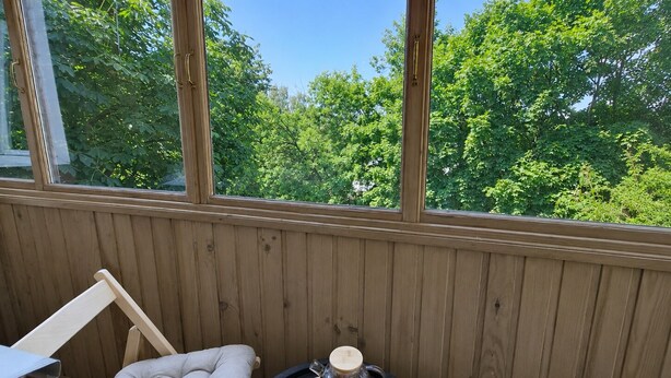 A wooden deck with a table set for breakfast, including croissants and tea, and two cushioned chairs. - Apartment near Komarovsky Market (Minsk)