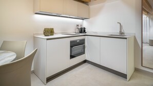 Una cocina moderna con armarios blancos, horno empotrado, cafetera y fregadero.