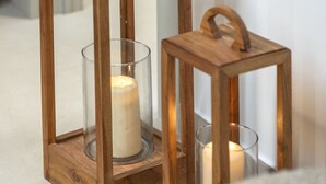 Dos faroles de madera con velas, sobre un suelo de baldosas.