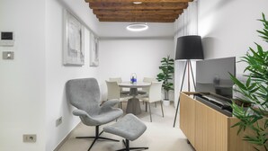 A modern living room with a wooden ceiling, a TV stand, a dining table with chairs, and a plant. - Palace Of The Elect Blue Apartment R&R (Venecia)