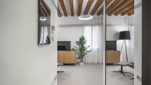 A modern living room with wooden beams, a flat-screen TV, a potted plant, and a floor lamp. - Palace Of The Elect Blue Apartment R&R (Venecia)