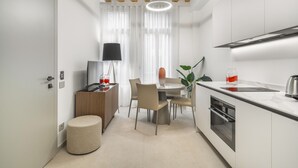 Una cocina moderna con vigas de madera, una zona de comedor con mesa y sillas, y un pequeño rincón de estar con un taburete.