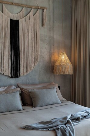 Ein Bett mit Kissen, ein Wandbehang aus Makramee und eine Pendelleuchte.