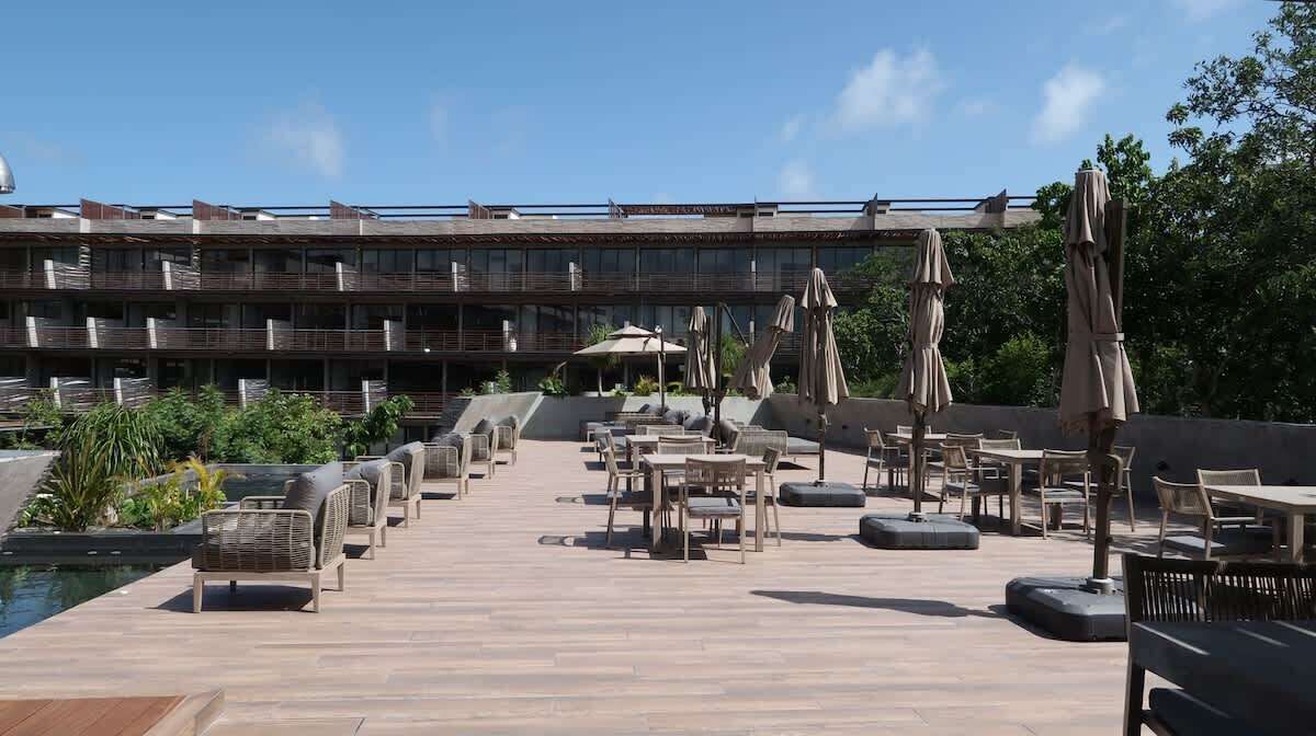 Een dakzwembad met ligbedden en parasols, een zwembad, en op de achtergrond een gebouw met meerdere balkons.