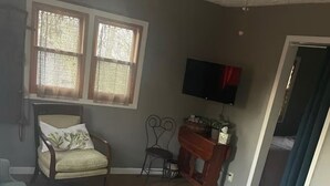 A living room with a wooden coffee table, a sofa, a chair, a TV, and a window with curtains.
