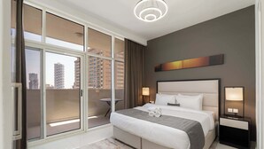 A modern hotel room with a large bed, a bedside table with lamps, a view of the city through floor-to-ceiling windows, and a cityscape view from the balcony. - StayShort - 1 Bed in JVC Sleeps 4 with City Views! (Jumeirah Village Circle)