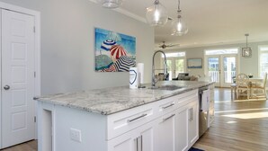 A kitchen with a marble countertop, white cabinetry, and pendant lighting. - Spacious Home with Private Pool Across from Ocean (Kure Beach)