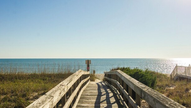 A wooden boardwalk leading to a beach with a clear view of the ocean. - Spacious Home with Private Pool Across from Ocean (Kure Beach)