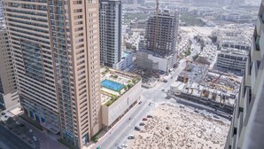 Un edificio de gran altura con varios pisos, un área de estacionamiento y una zona de construcción con grúas.