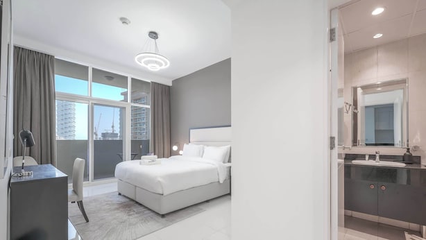 Una habitación de hotel moderna con una cama grande, un escritorio y un baño con espejo y lavamanos.