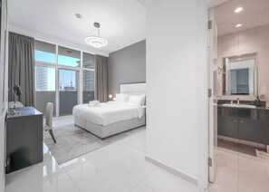 Ein modernes Hotelzimmer mit einem großen Bett, einem Schreibtisch und einem Badezimmer mit Spiegel und Waschbecken.