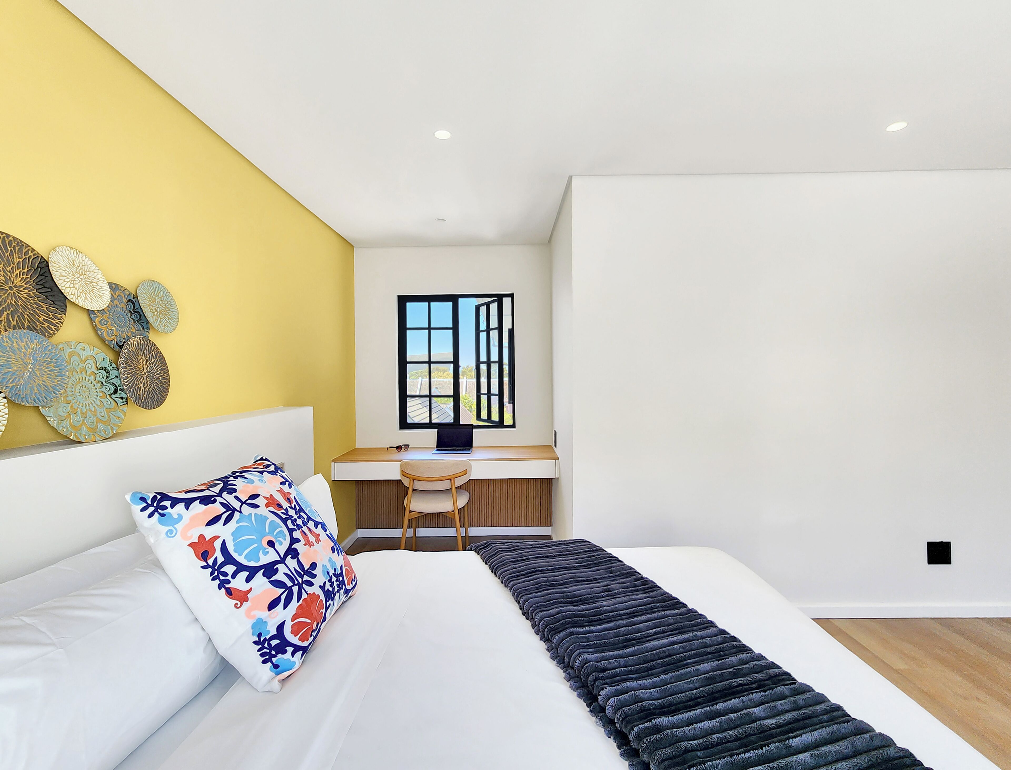 Un dormitorio moderno con cama, escritorio y vistas al exterior.