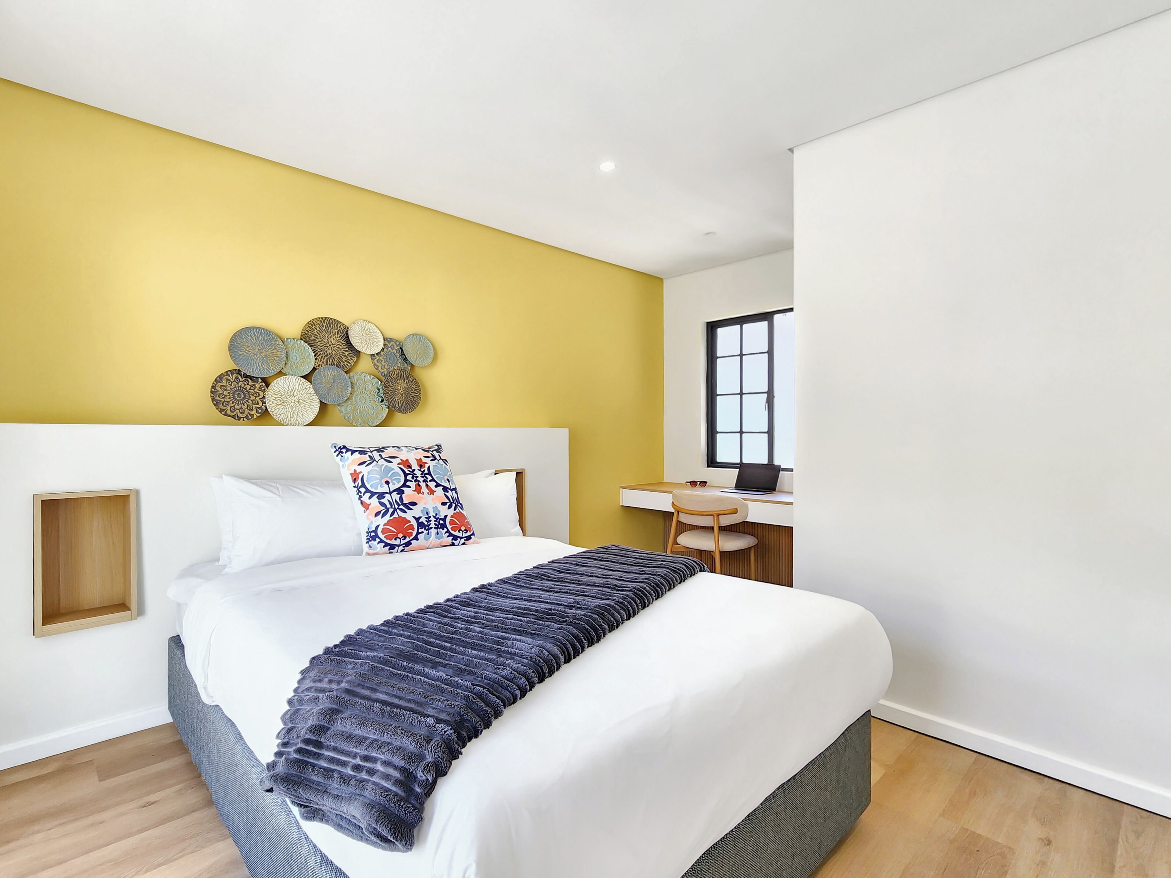 A modern bedroom with a bed, a desk, and a window.