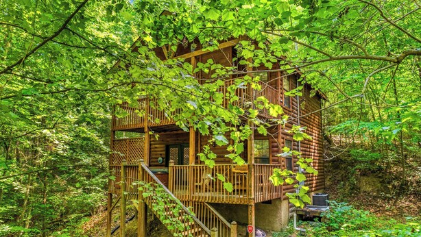 Une cabane en bois dotée d’un balcon, entourée d’une forêt dense.