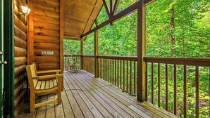 Une terrasse en bois, agrémentée d’un banc et d’une rambarde, entourée d’une végétation luxuriante.