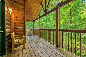Eine Holzterrasse mit Bank und Geländer, umgeben von üppigem Grün.