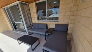 Ein überdachter Außenbereich mit einer Couch, einem Tisch und einer Bank.
