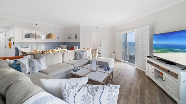 A modern living room with a large flat-screen TV, a sectional sofa, and a dining area. - Palm Beach 41A by Liquid Life (Orange Beach)