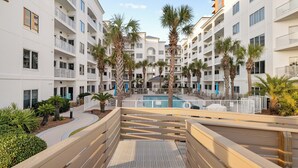 A multi-story hotel with balconies, a central pool, and palm trees. - Palm Beach 41A by Liquid Life (Orange Beach)