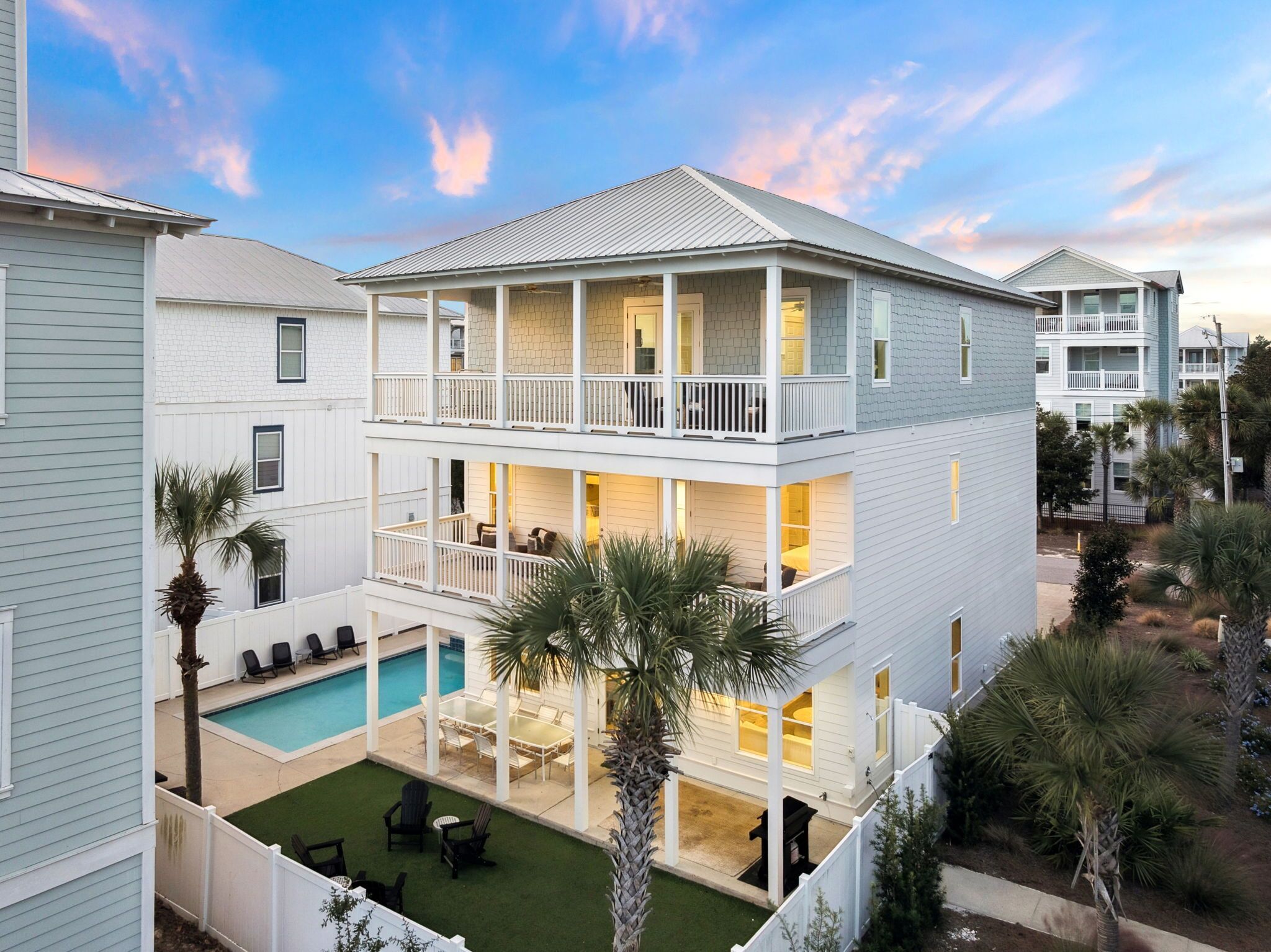 A two-story house with a balcony, a swimming pool, and a well-maintained lawn.