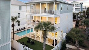 A two-story house with a balcony, a swimming pool, and a well-maintained lawn. - Spacious Retreat Made for Memory-Making Moments w/ Pool, Spa, and Game Room (Inlet Beach)
