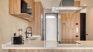 A modern kitchen with wooden cabinetry, a white countertop, a built-in oven, and a stainless steel range hood. - Brand New 1 BR Condo in Roma Norte - Rooftop (Mexico City)