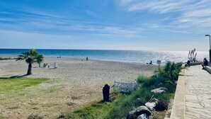 Una playa con cielo despejado, un camino y algunas personas caminando.