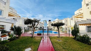 Zona residencial con piscina, edificios blancos y un sendero rojo.