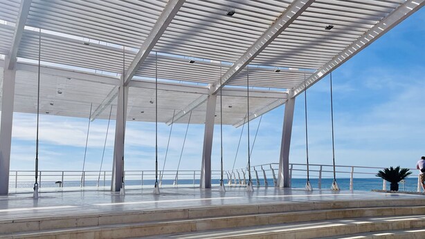 Un espacio al aire libre cubierto con escalones que conducen a una barandilla con vista al mar.