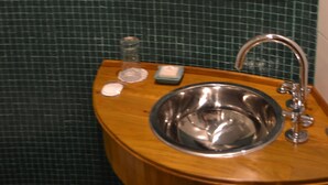 A bathroom with a wooden vanity, a stainless steel sink, and a mirror with wooden frame. - Individual room in the Heart of the town (El Calafate)