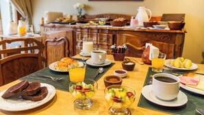 A breakfast setting with various dishes, including toast, fruit, and coffee, on a wooden table. - Standard Double Room (Queen Bed) (El Calafate)