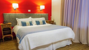 A hotel room with a large bed, two bedside tables, a nightstand, and a red accent wall. - Standard Double Room (Queen Bed) (El Calafate)