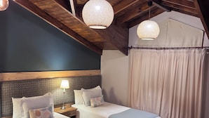 Una habitación acogedora con dos camas, vigas de madera en el techo e iluminación colgante de tejido.