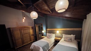 Habitación de hotel con dos camas, armario de madera y lámparas colgantes.